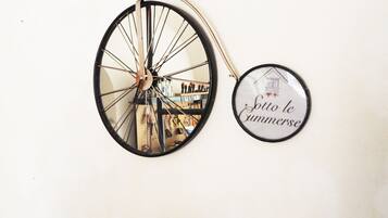 A wall-mounted bicycle with a mirror reflecting a room and a circular sign with text.