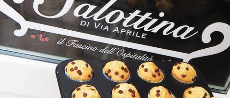 A bakery window with the sign "la Salottina DI VIA APRILE" and a display of freshly baked muffins.