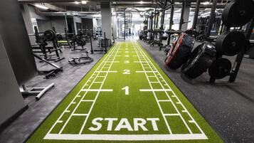 Un gimnasio con una pista de atletismo verde marcada con números y un cartel que dice 'START'.