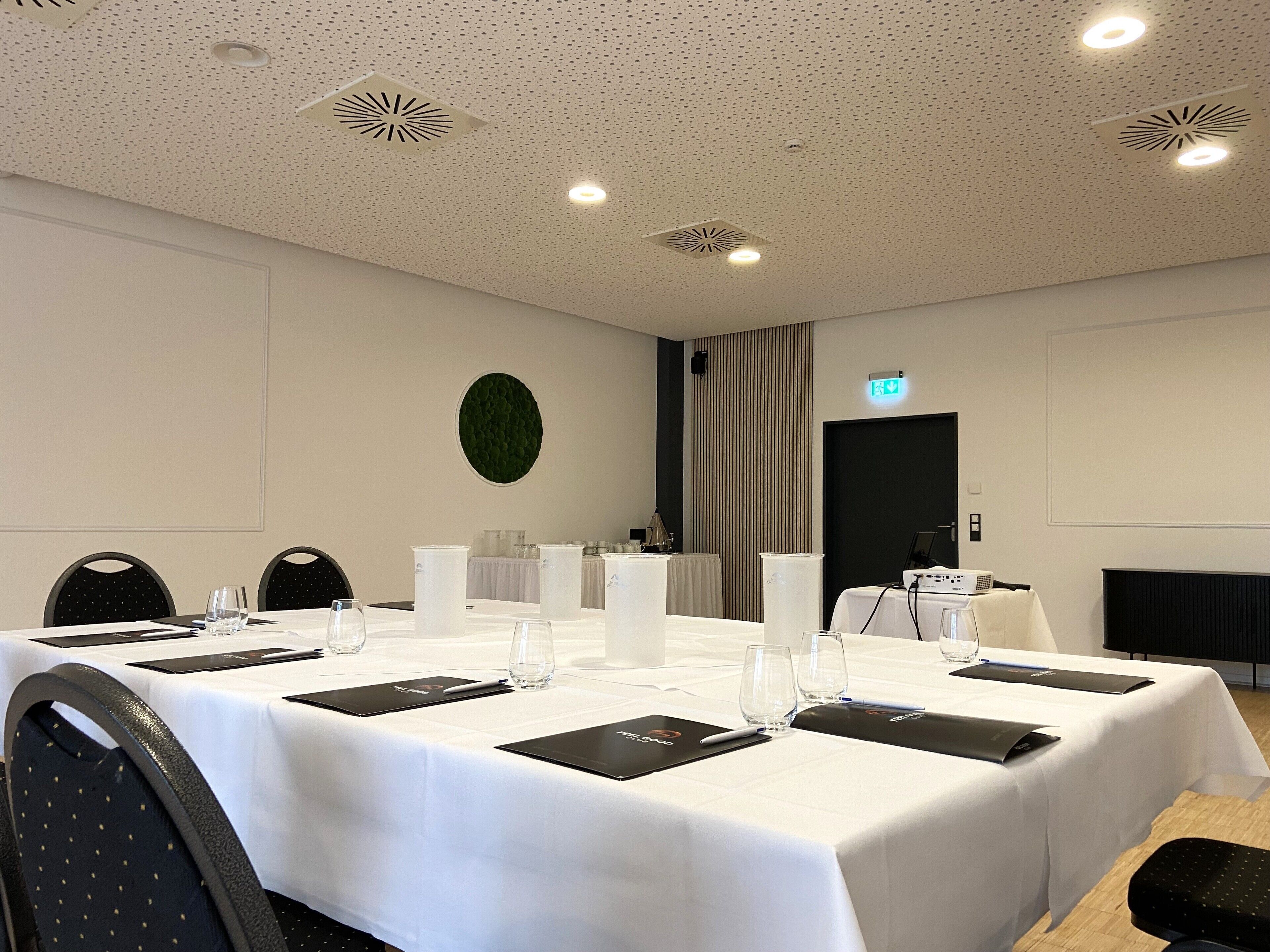 A conference room with a long table set for meetings, equipped with chairs, water glasses, and nameplates.