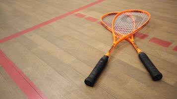 Två orangefärgade tennisracketar ligger på ett trägolv med röda markeringar.