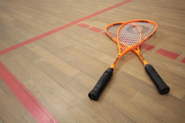Two orange tennis rackets on a wooden floor with red markings. - Feel Good Hotel (Chemnitz)