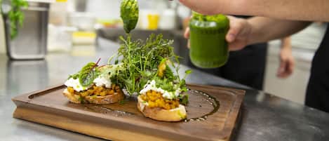 A chef preparing a dish with a wooden board, a bottle, and a spoon.