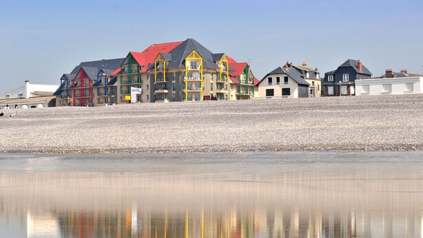 A row of colorful buildings with balconies along a pebbled beach. - Madame Vacances Residence Les Terrasses de la Plage (Cayeux-sur-Mer)