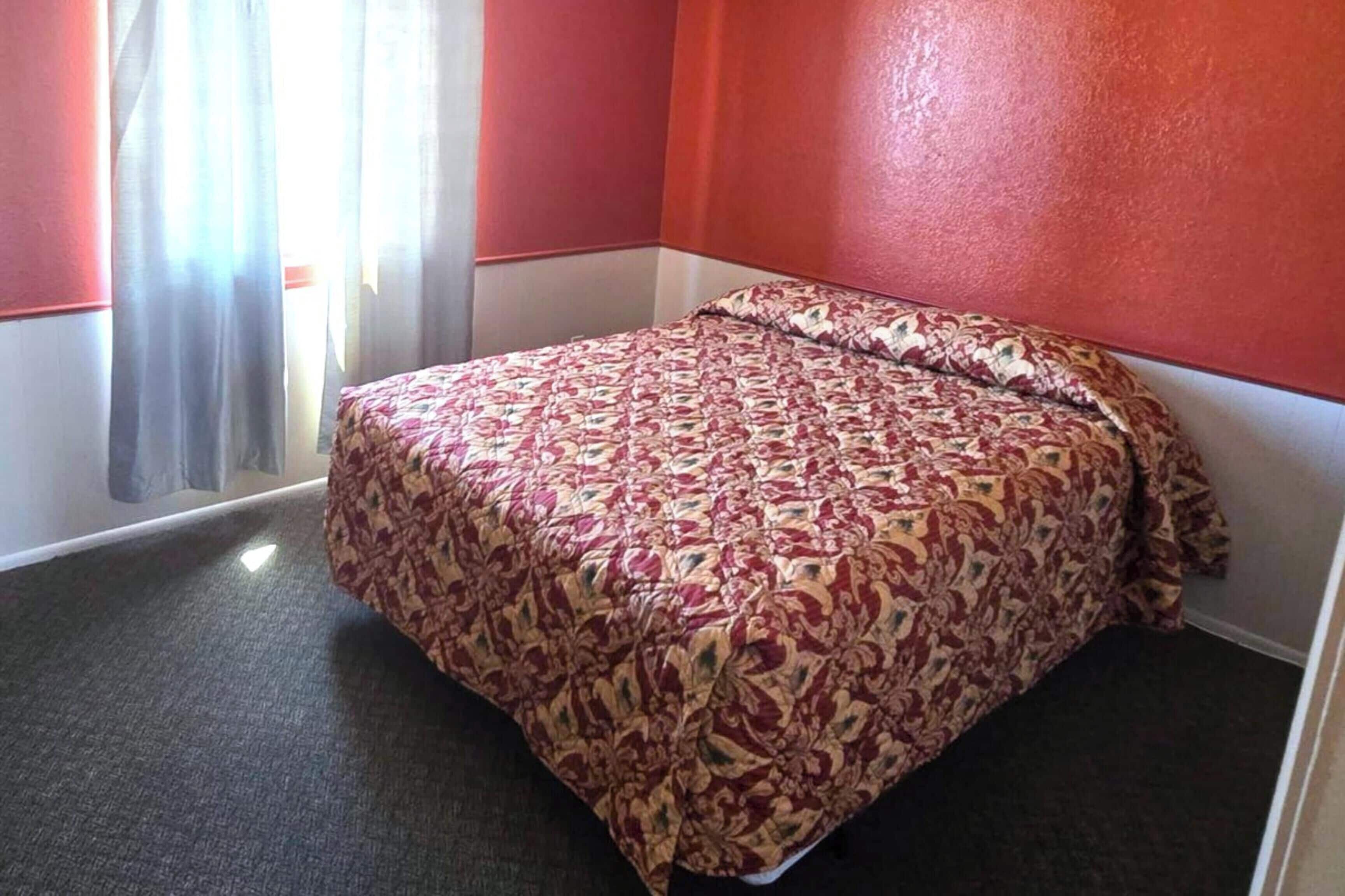 Une chambre d’hôtel avec un lit, des rideaux et un sol recouvert de moquette.