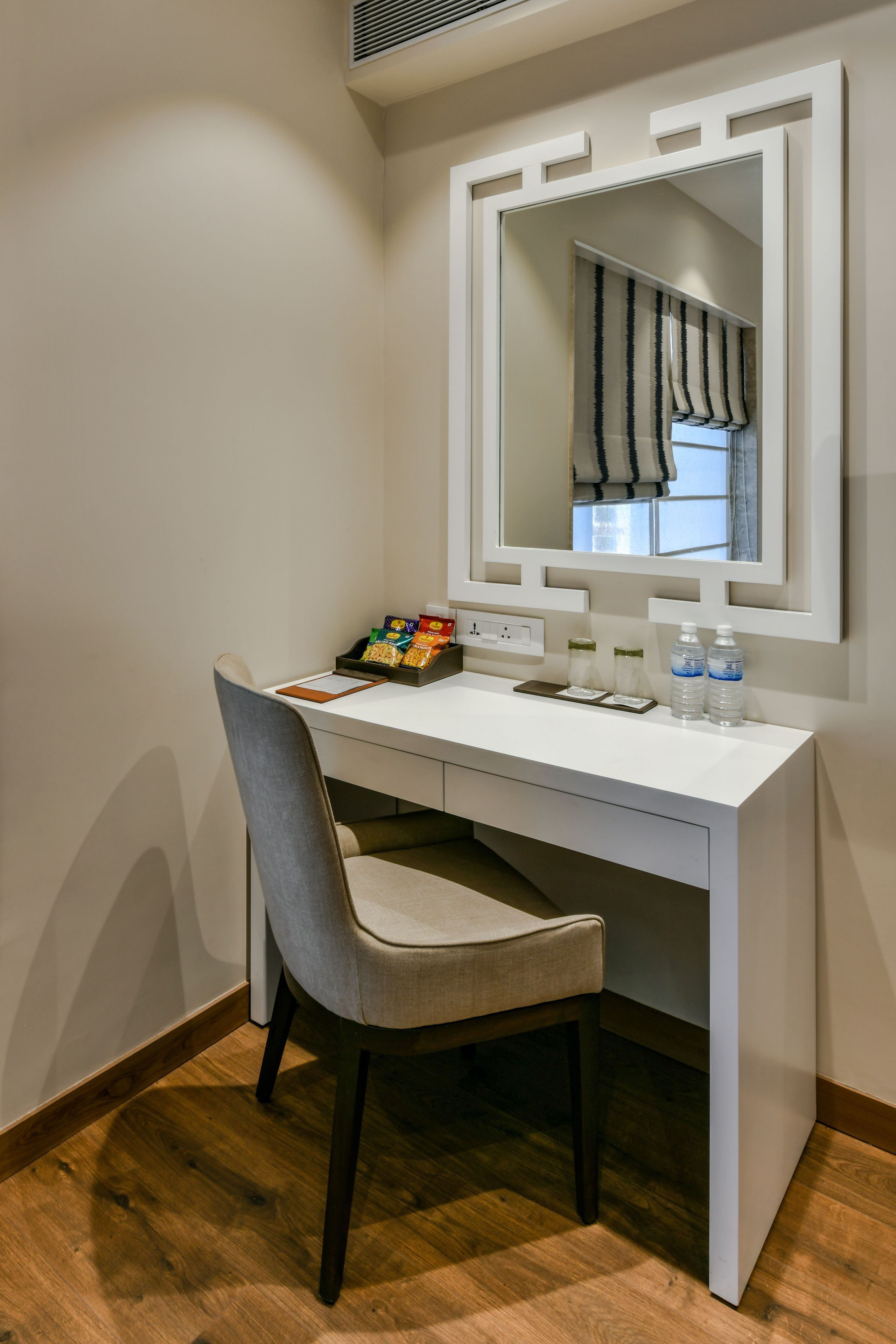 A compact, modern bathroom with a white vanity, a mirror, and a chair.