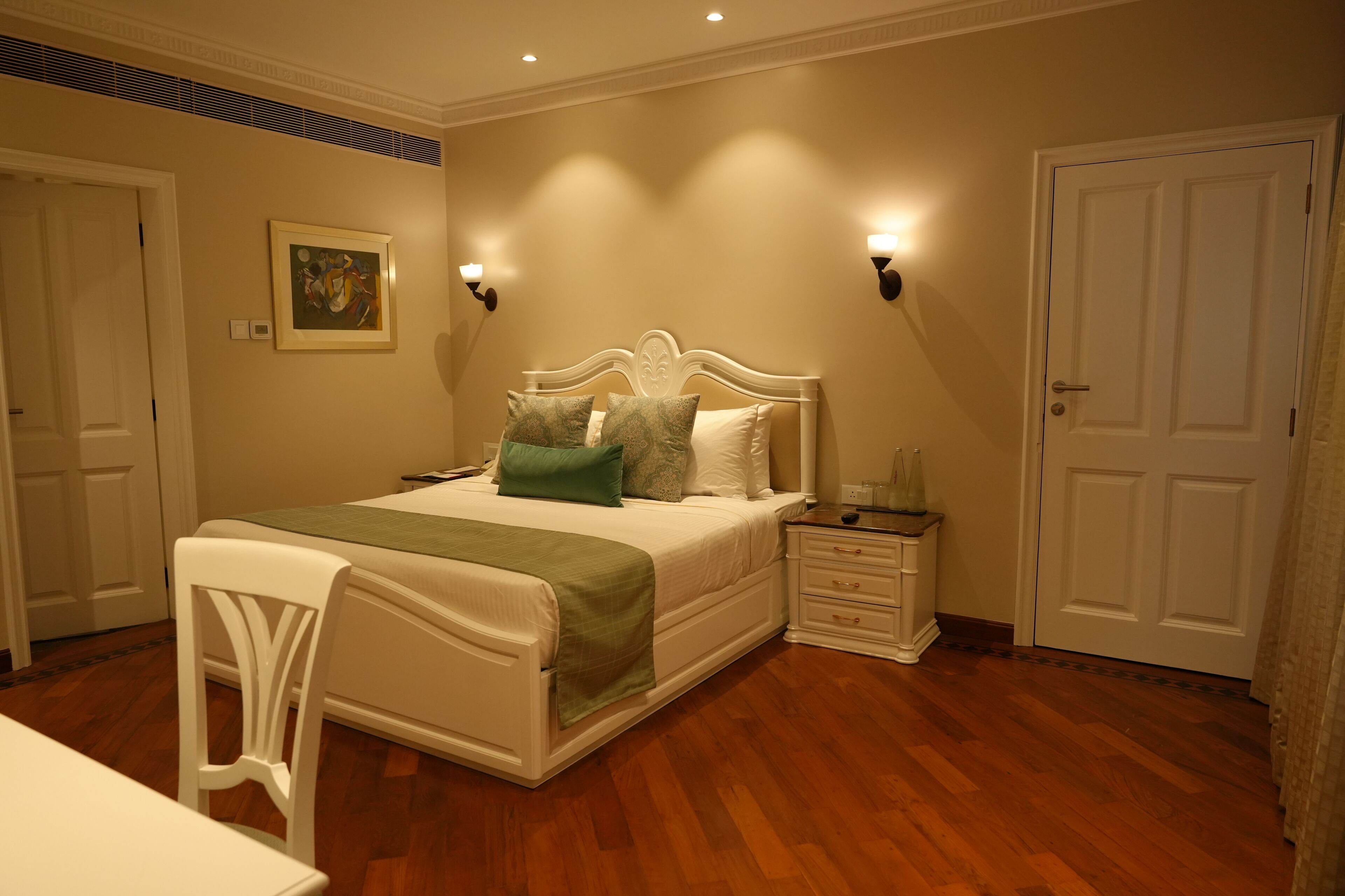 Un dormitorio con cama, mesitas de noche, una silla y una puerta.