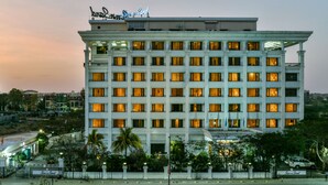 A multi-story hotel with a classic architectural design, featuring a prominent sign at the top. - Sun N Sand Shirdi (Rahata)