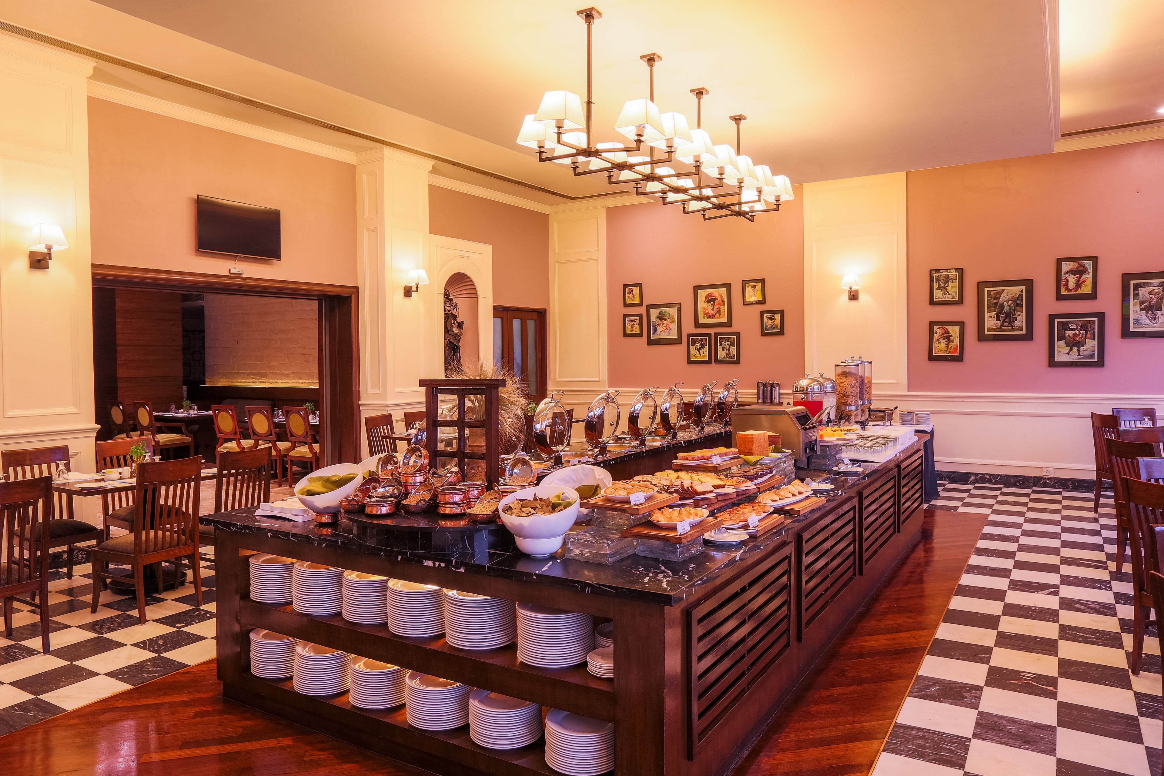 A buffet area with a checkered floor, wooden furniture, and a variety of food items displayed on a marble counter.