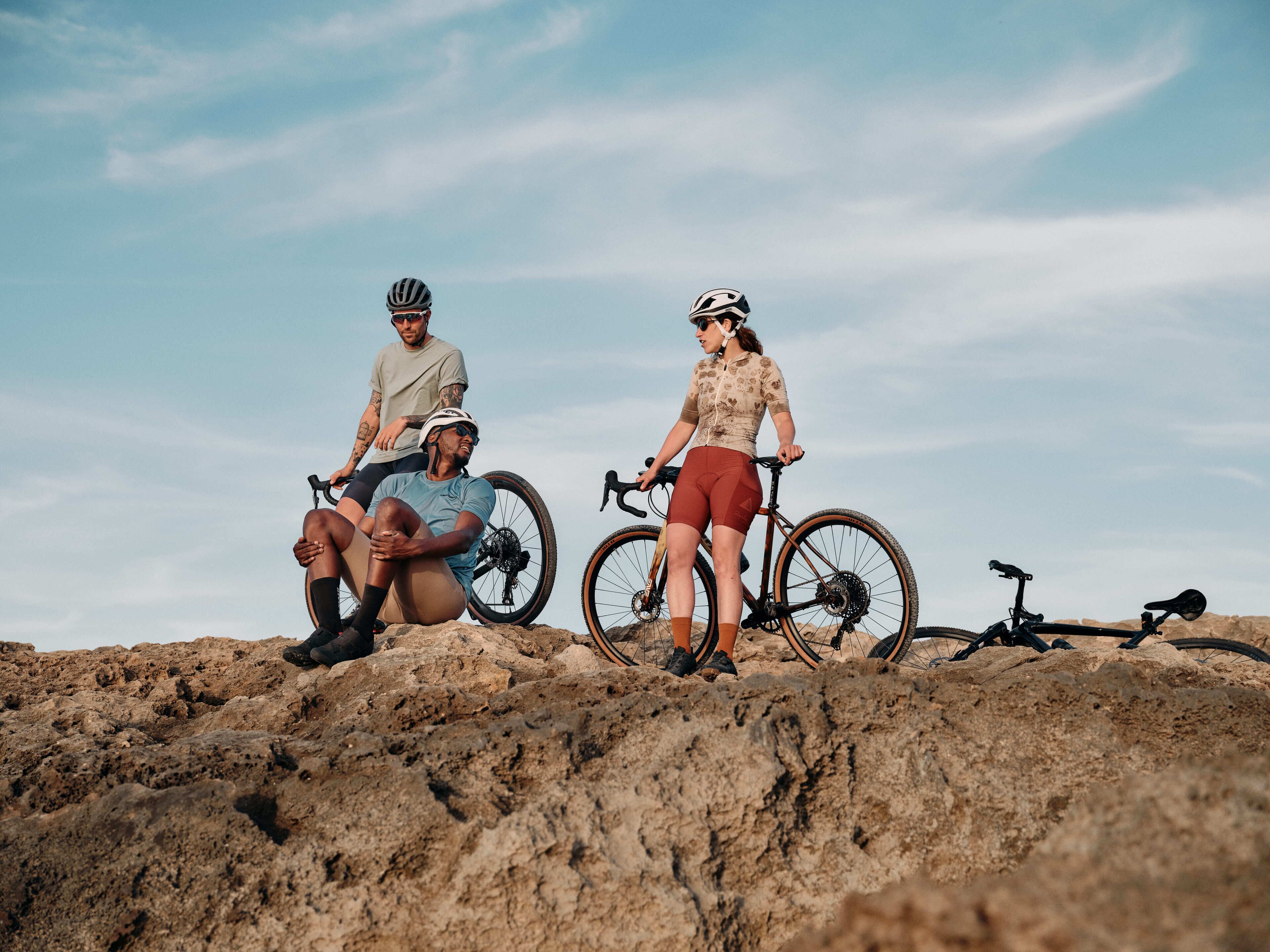 Two people sitting on a rocky surface with bicycles, under a clear sky.