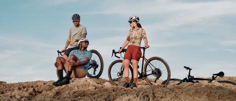 Two people sitting on a rocky surface with bicycles, under a clear sky.