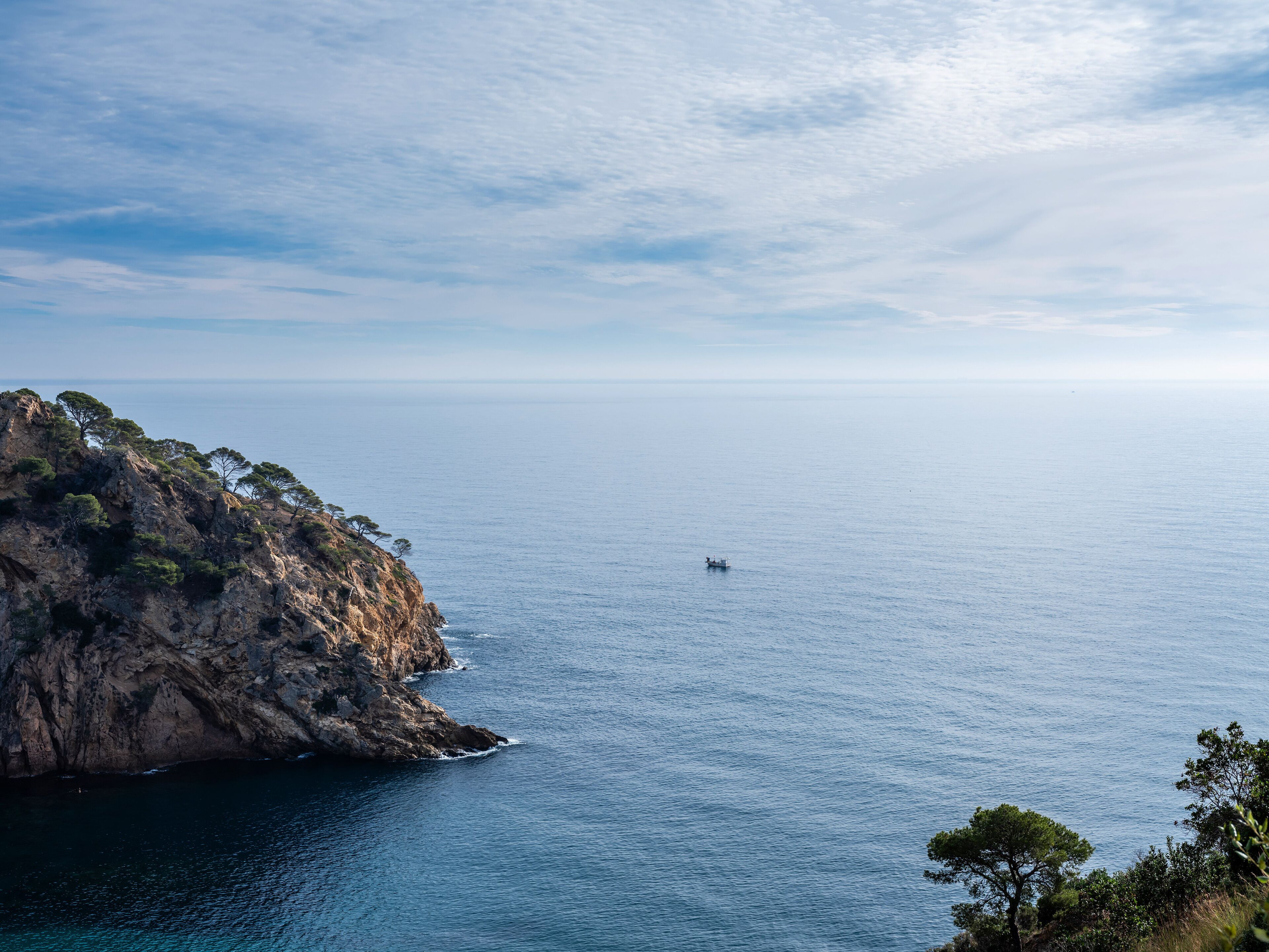 A coastal landscape with rocky cliffs and a clear view of the sea.