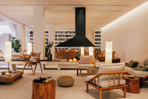 A modern interior with a central fireplace, wooden furniture, and a bookshelf filled with decorative items. - Zel Costa Brava (Tossa de Mar)