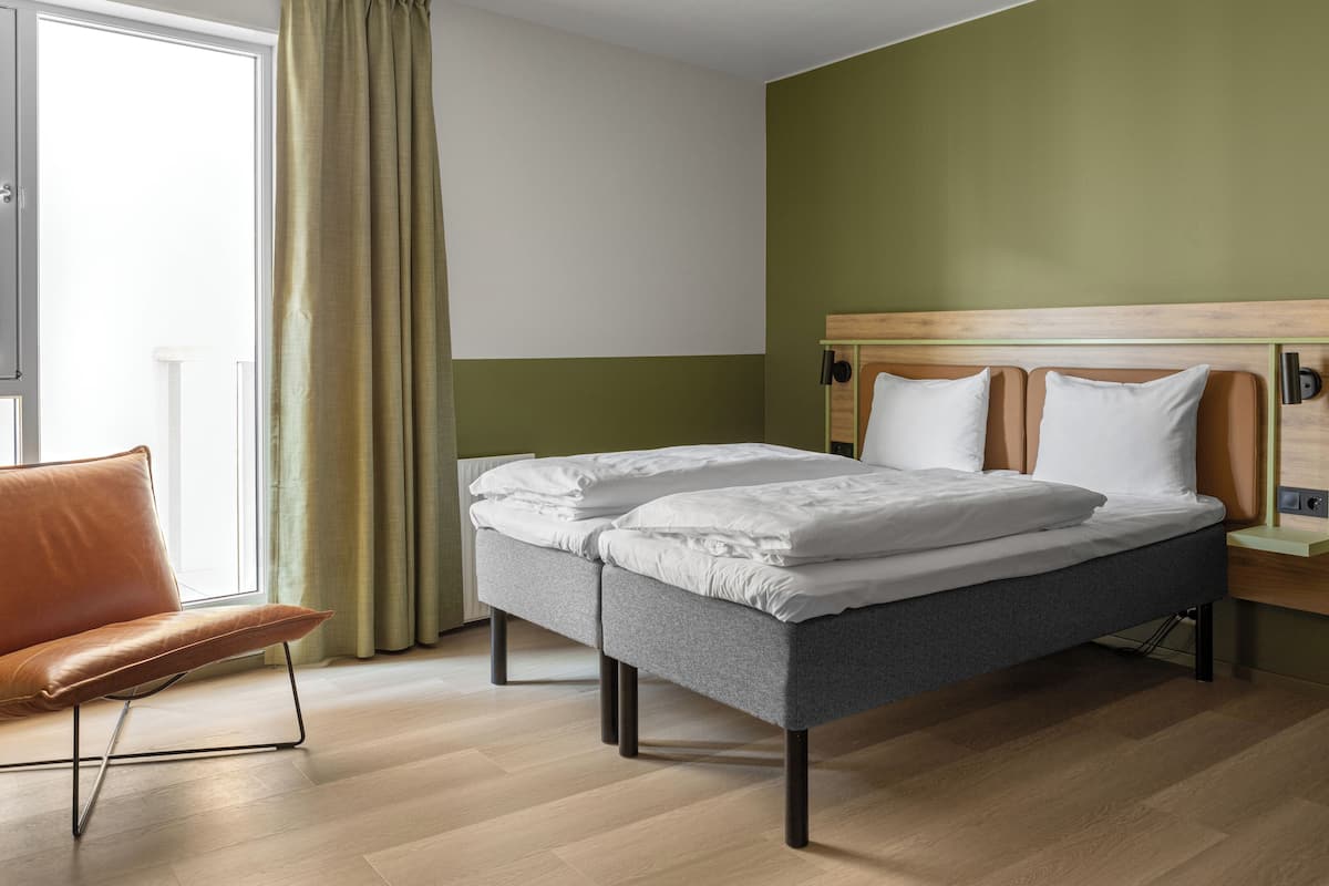 Una habitación de hotel moderna con cama, una silla y un escritorio.