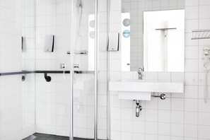 A modern bathroom with a glass shower enclosure, a white sink with a mirror, and a towel rack. - Comfort Hotel Trondheim (Trondheim)