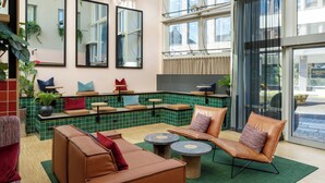 Un área de descanso moderna con asientos, espejos y paredes de azulejos verdes.