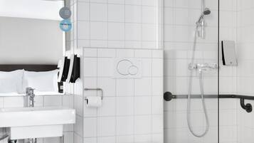 A modern bathroom with a white sink, toilet, and shower. There are two towel racks and a toilet paper holder.
