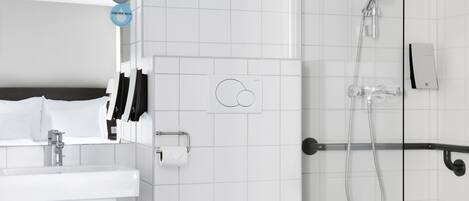 A modern bathroom with a white sink, toilet, and shower. There are two towel racks and a toilet paper holder.