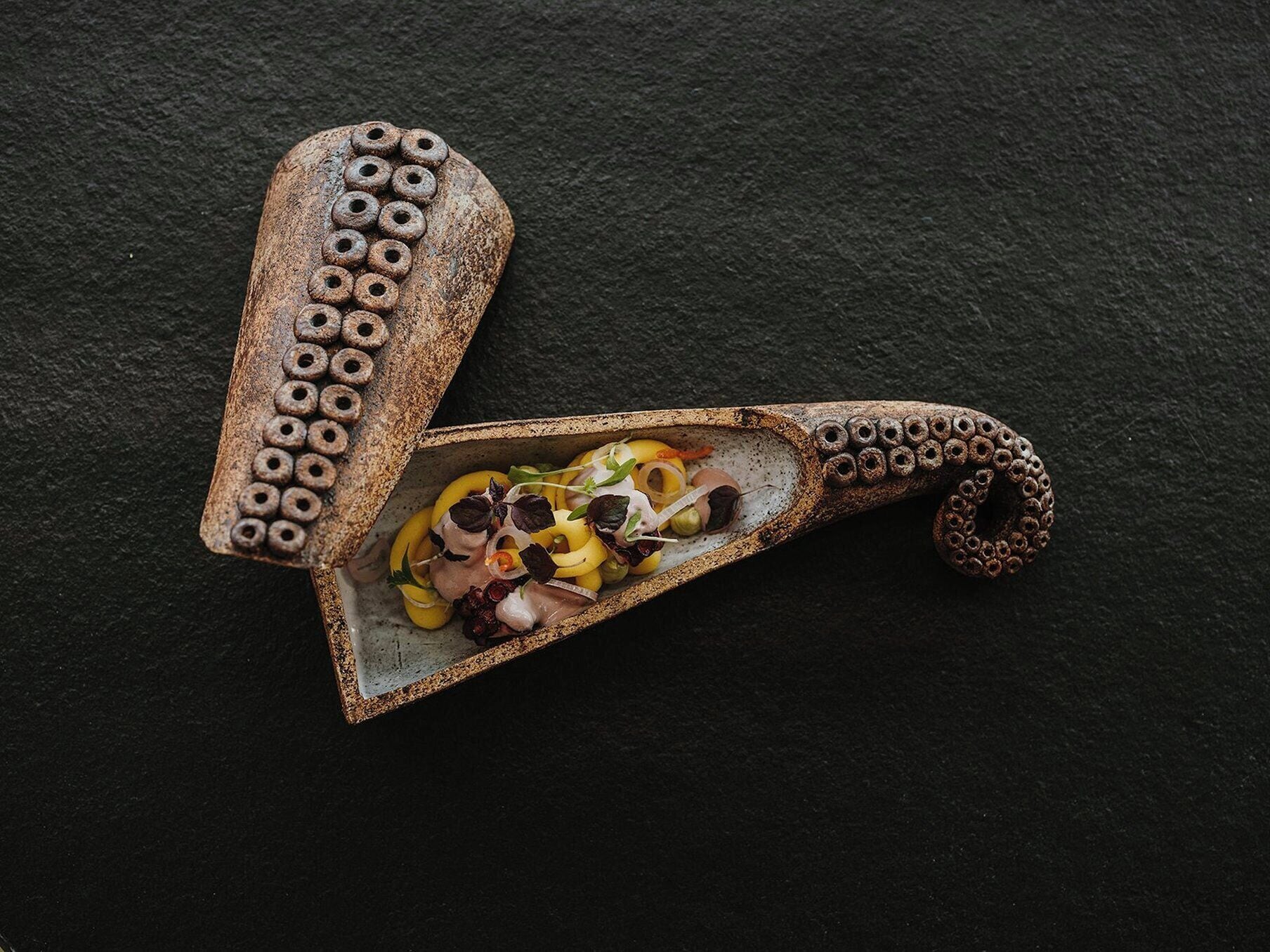 A rustic wooden spoon with a handle containing a salad.