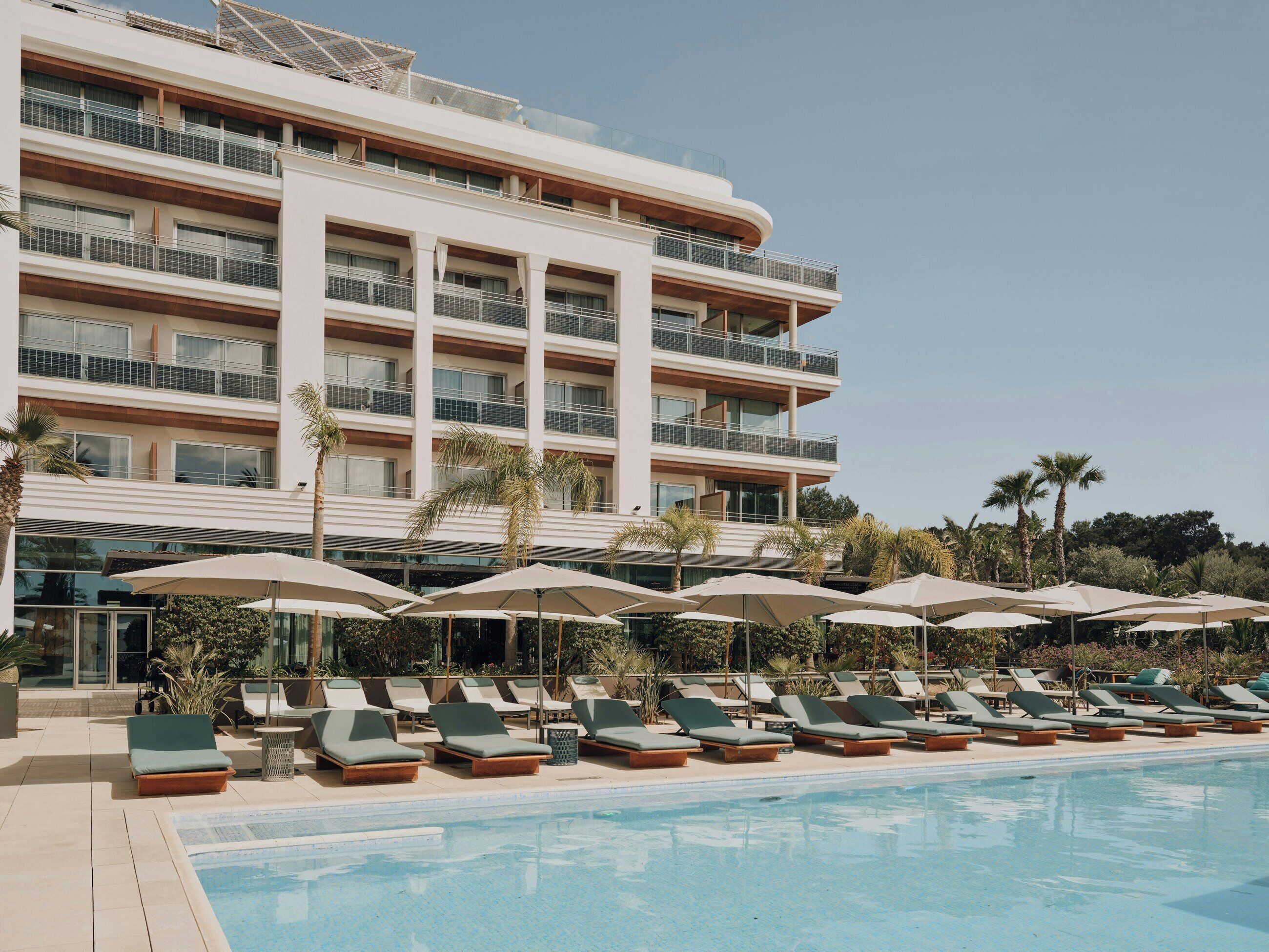 Un hotel con piscina, lettini e ombrelloni.