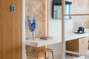 A modern reception desk with a wooden panel, a vase with blue flowers, a book, and a coffee machine.