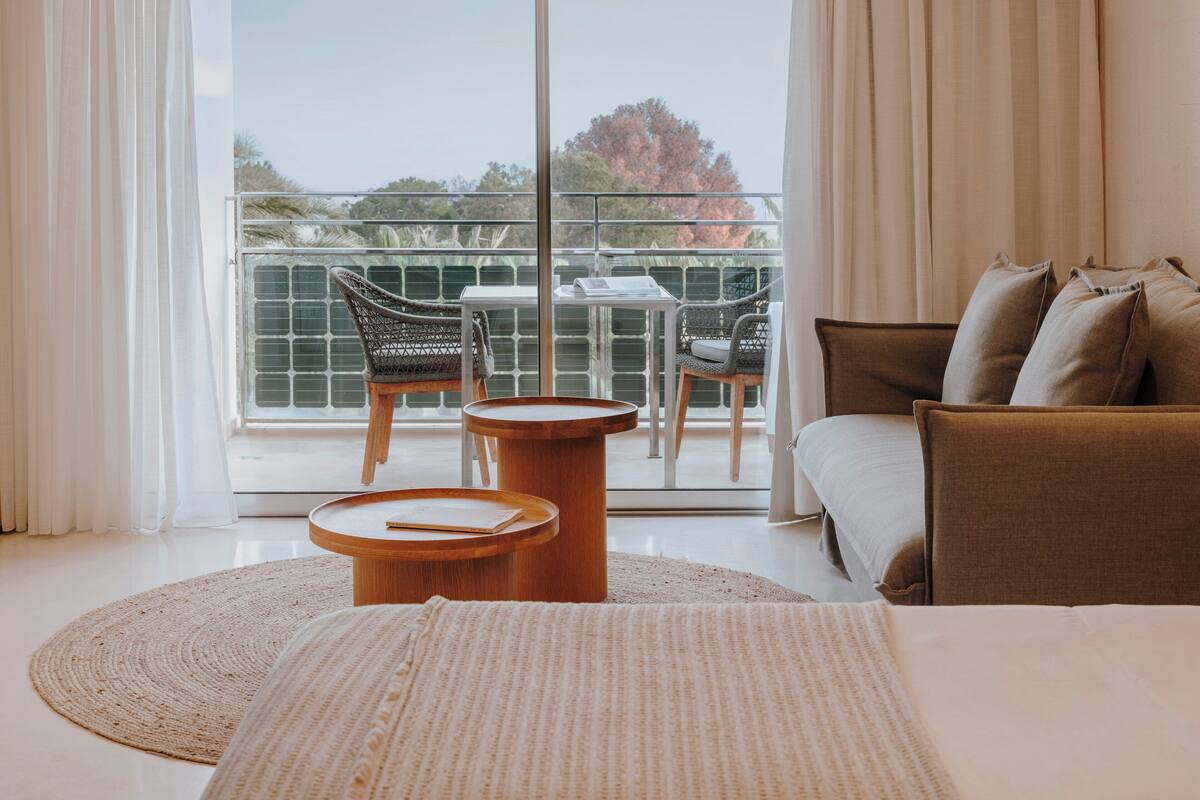 Une chambre avec un balcon, un canapé, une table ronde en bois et une chaise.