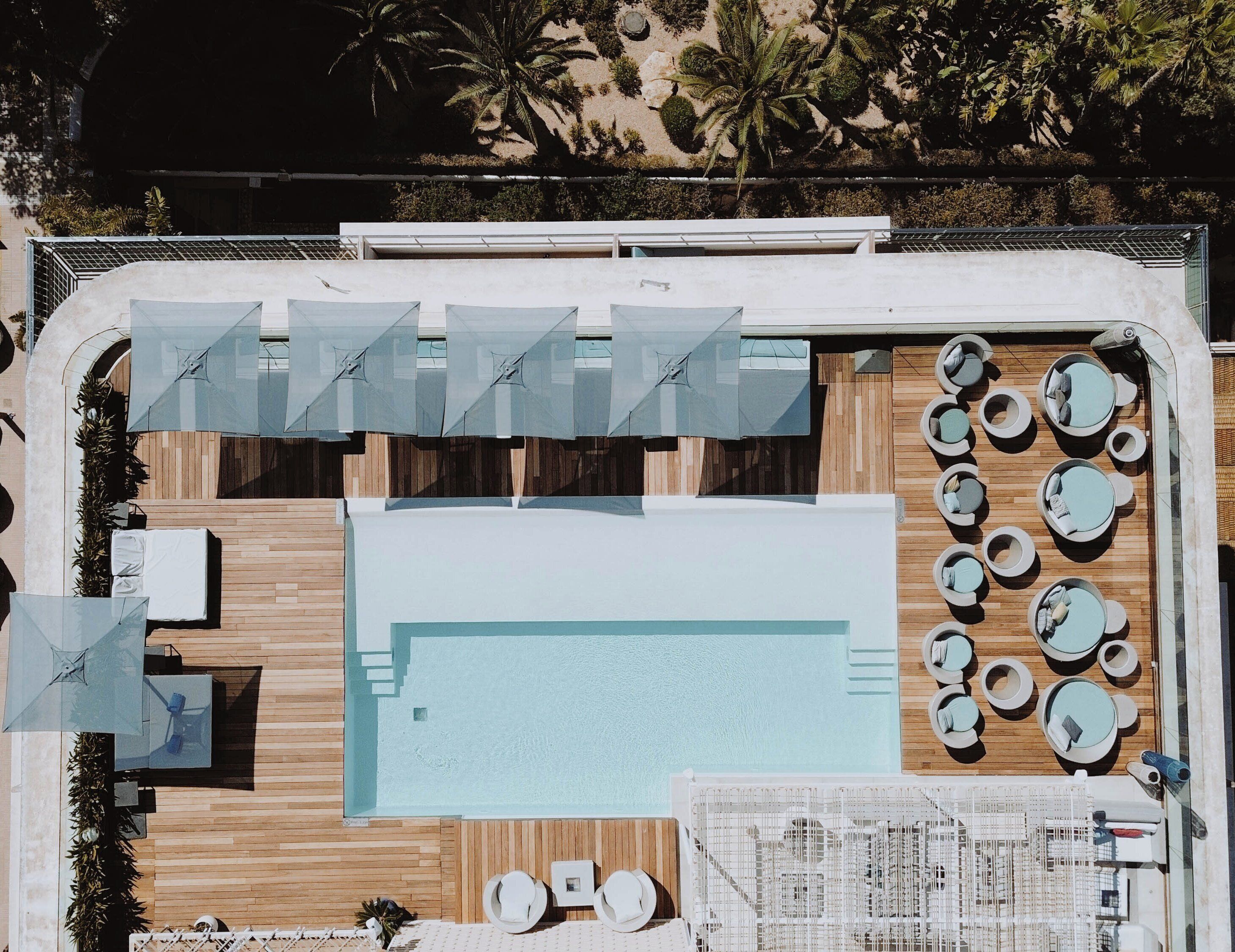 Uma área de piscina no terraço com várias espreguiçadeiras, guarda-sóis e um deck de madeira.
