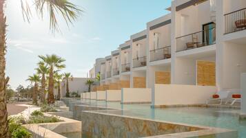 Un hotel moderno con zona de piscina, varios balcones y palmeras.