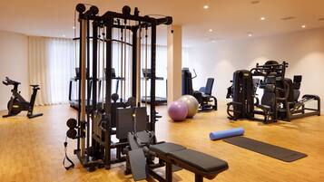 A gym with various exercise equipment, including a cable machine, weight bench, and exercise balls.