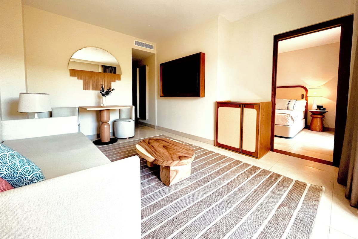 Habitación de hotel con cama, escritorio, silla, televisión y espejo.