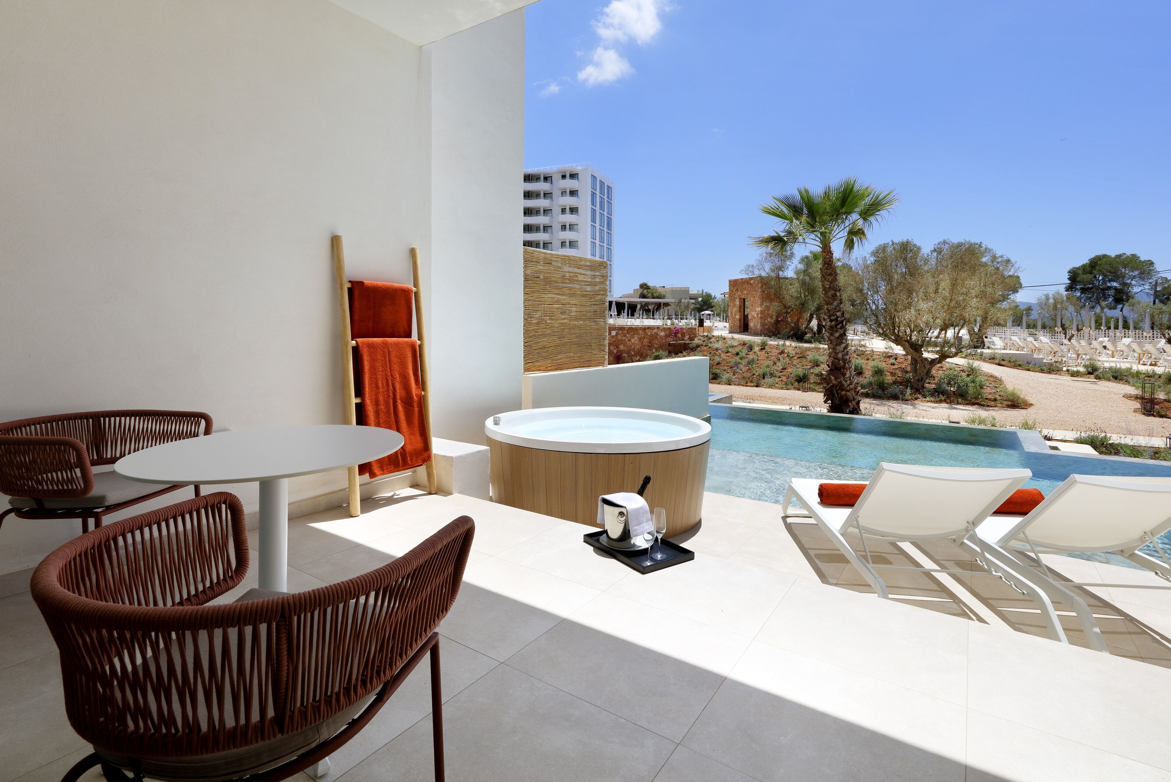 A modern outdoor seating area with a hot tub, lounge chairs, and a pool view.