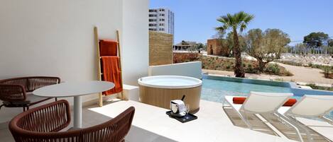 A modern outdoor seating area with a hot tub, lounge chairs, and a pool view.