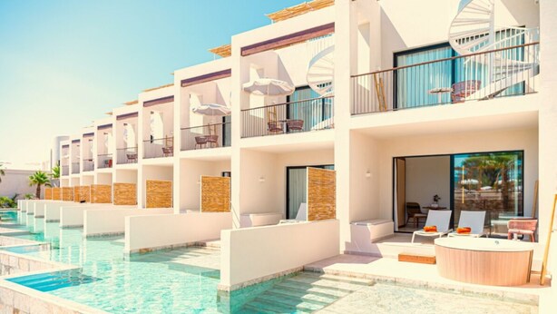 A hotel with multiple balconies, a swimming pool, and outdoor seating areas.
