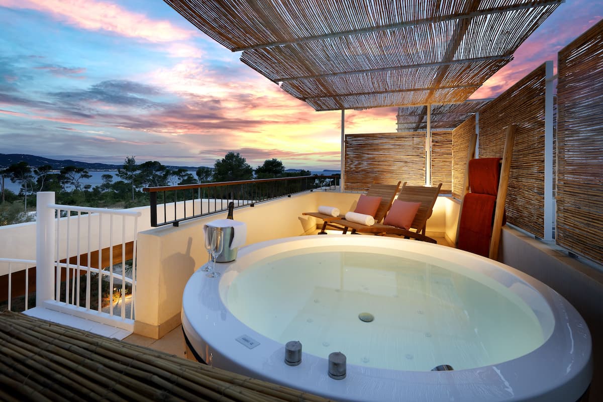 Un jacuzzi con vistas al paisaje, un área de estar techada y una barandilla blanca.