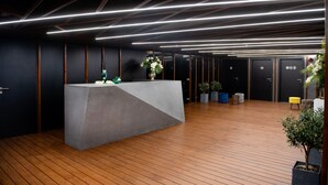 Ein moderner Empfangsbereich mit einer Betonrezeption, Holzböden und einer Decke mit linearer Beleuchtung.