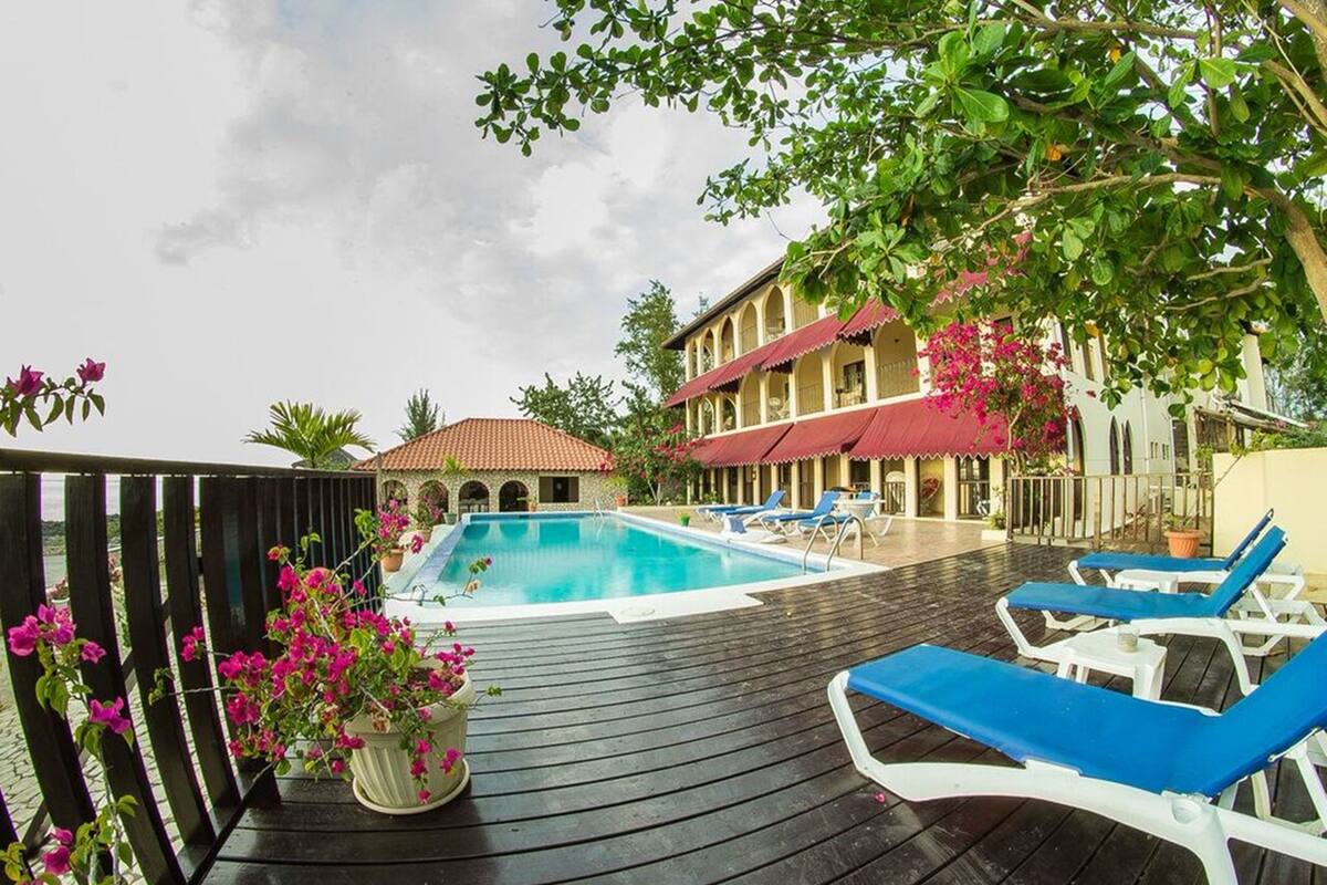 Un espace piscine avec des chaises longues et un bâtiment doté d’un toit rouge.