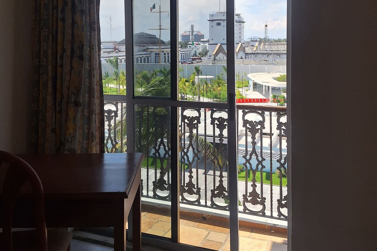 A room with a large window overlooking a balcony with a metal railing.