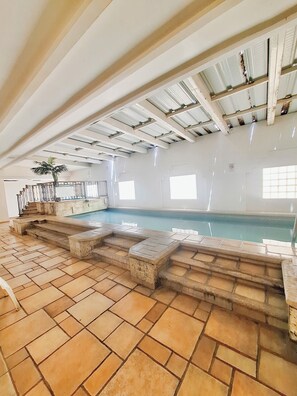 Una piscina techada, sillones reclinables de piscina