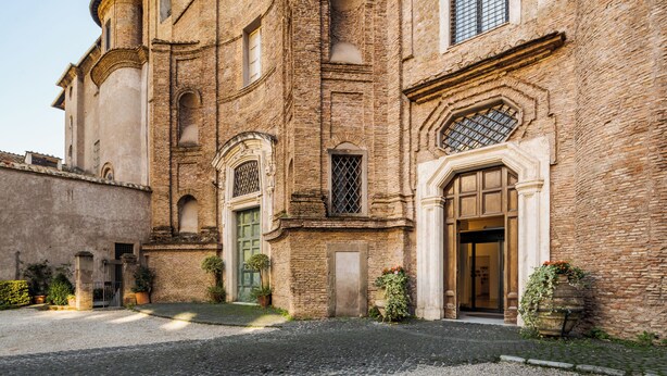 A historic building with a courtyard, arched windows, and a prominent entrance. - Donna Camilla Savelli – VRetreats (Rome)