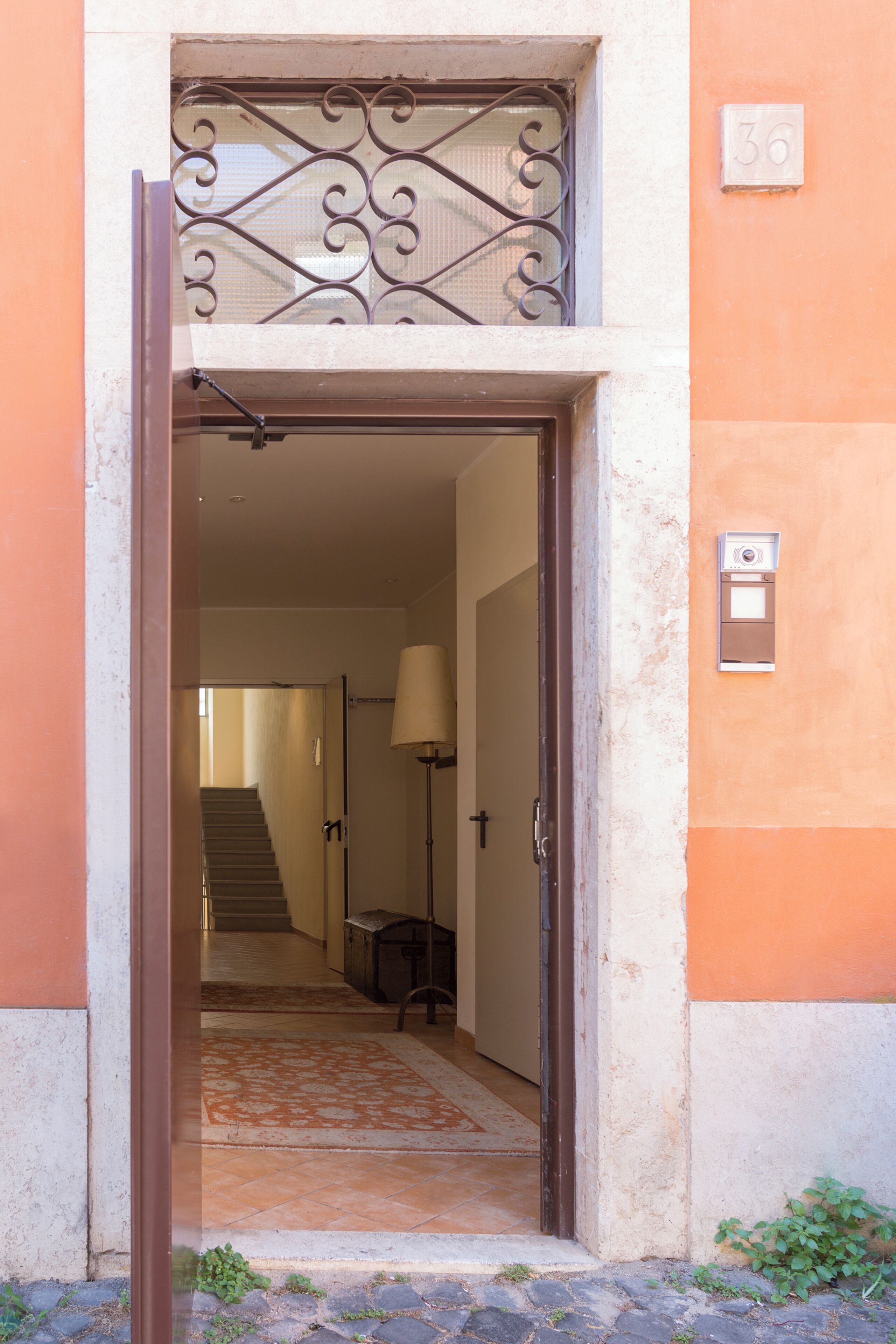 An open doorway leading to a staircase, a lamp, and a mailbox on the wall.