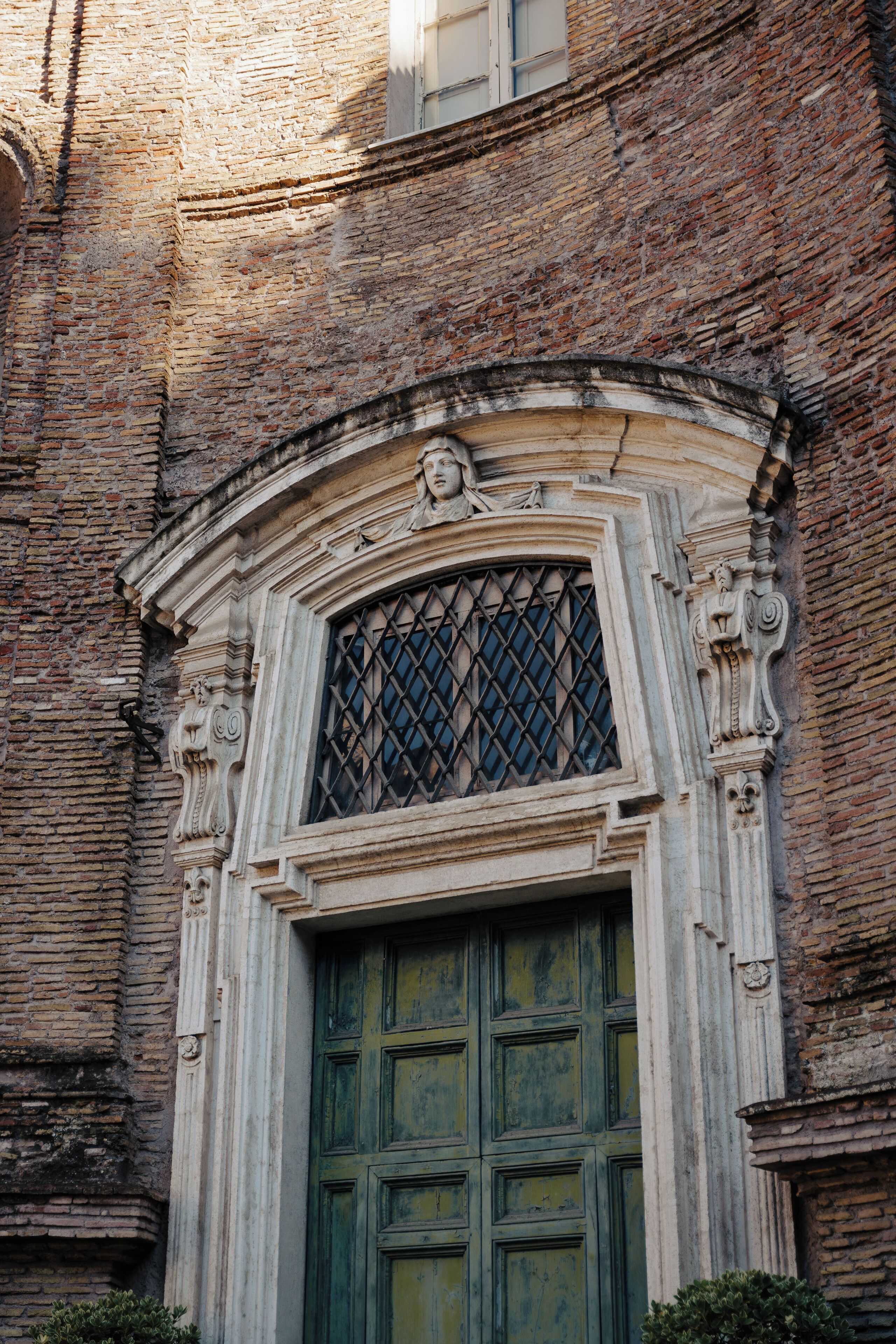 Un bâtiment historique doté d’une grande fenêtre en arc de cercle et d’une porte verte.