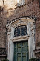 A historic building with a large arched window and a green door.