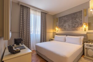 A hotel room with a large bed, a bedside table with a coffee maker, and a large mirror on the wall.