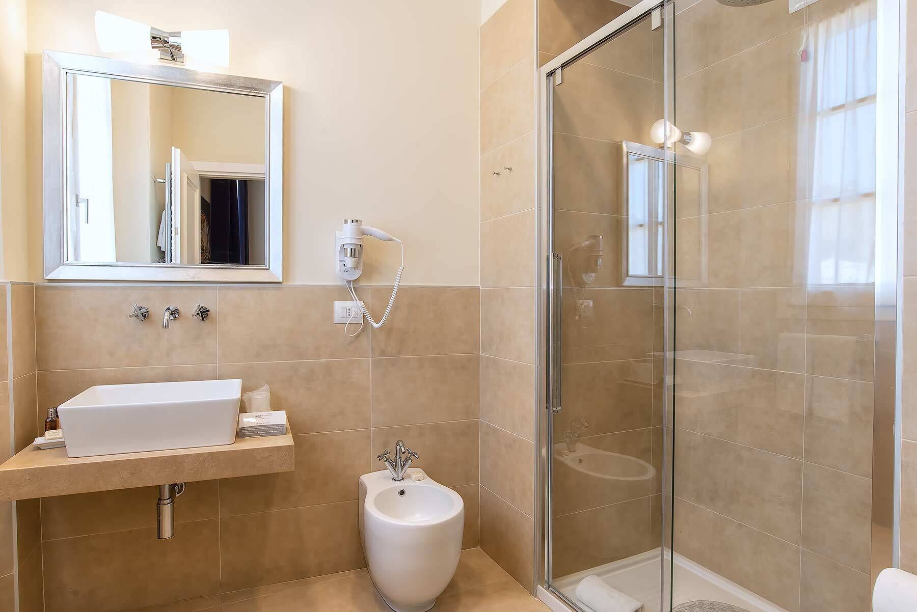 Un baño moderno con cabina de ducha de vidrio, un lavabo con espejo y un bidé.