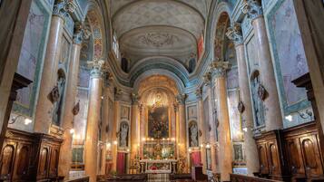 An ornate church interior with high ceilings, marble columns, and a central altar.