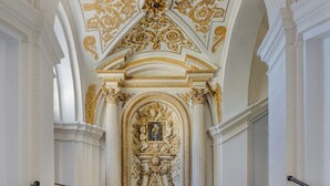 A grand staircase with ornate gold detailing and classical columns, leading to a richly decorated room. - Donna Camilla Savelli – VRetreats (Rome)