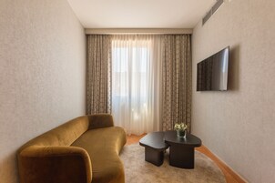 A modern living room with a sofa, a coffee table, and a flat-screen TV mounted on the wall.