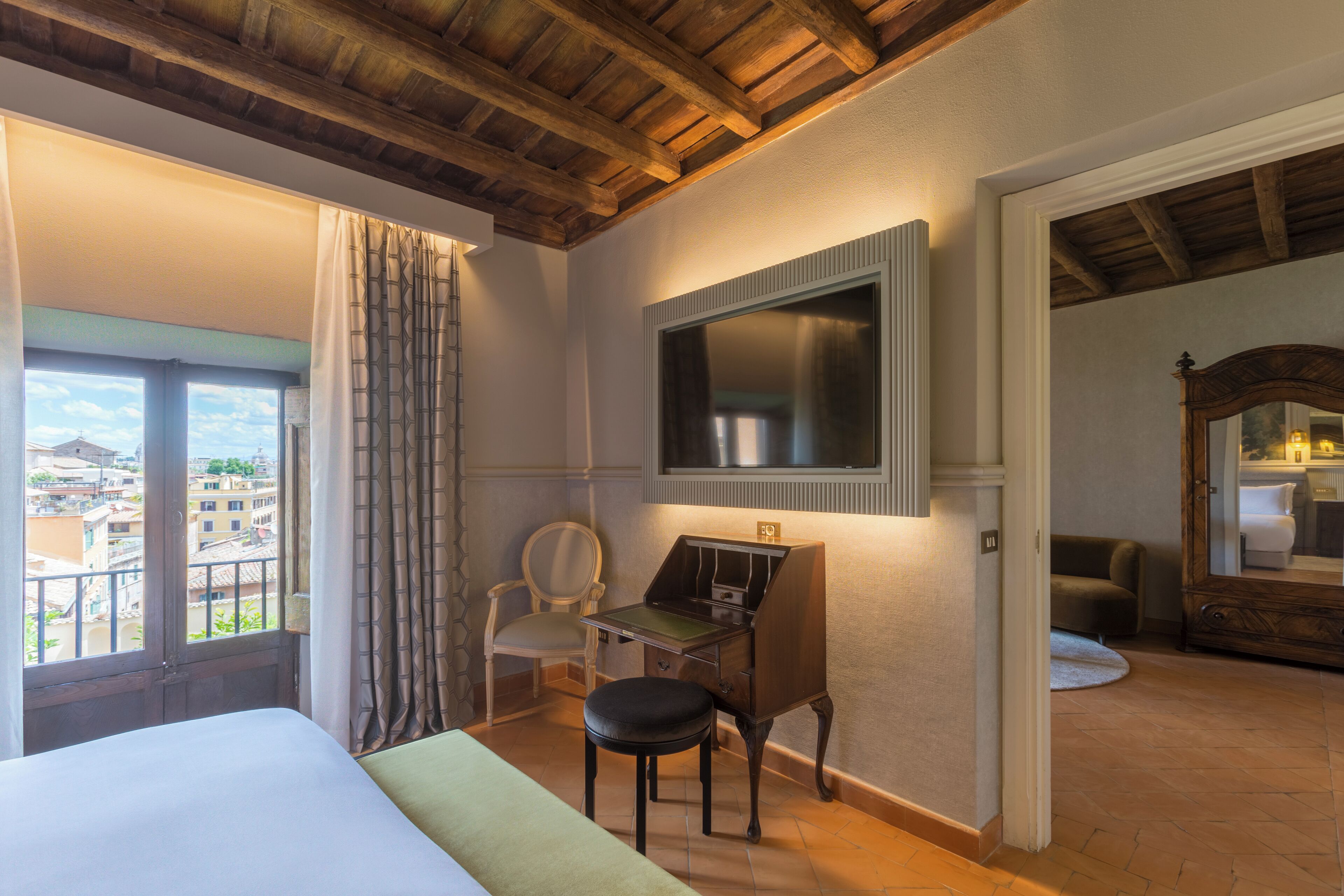 Une chambre d’hôtel avec un lit, un bureau, une chaise, une télévision et une vue sur la ville.