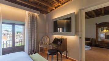 Une chambre d’hôtel avec un lit, un bureau, une chaise, une télévision et une vue sur la ville.