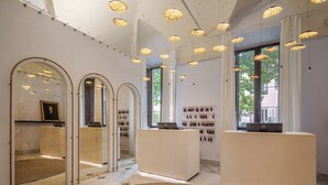 A modern interior with arched mirrors, a reception desk, and pendant lighting. - Donna Camilla Savelli – VRetreats (Rome)